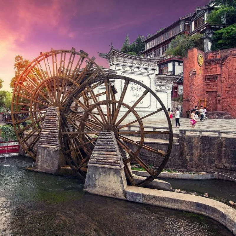 Lijiang Ancient Town 麗江古城著名的大水車景觀,巨大的木製水車在清澈河道旁緩緩轉動,周圍是傳統納西族建築與古城街景。