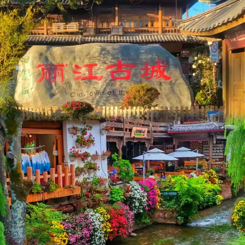 Lijiang Old Town 2 麗江古城著名的大水車景觀,巨大的木製水車在清澈河道旁緩緩轉動,周圍是傳統納西族建築與古城街景,遊客漫步其間,展現麗江古城融合歷史文化與自然水景的特色風光。