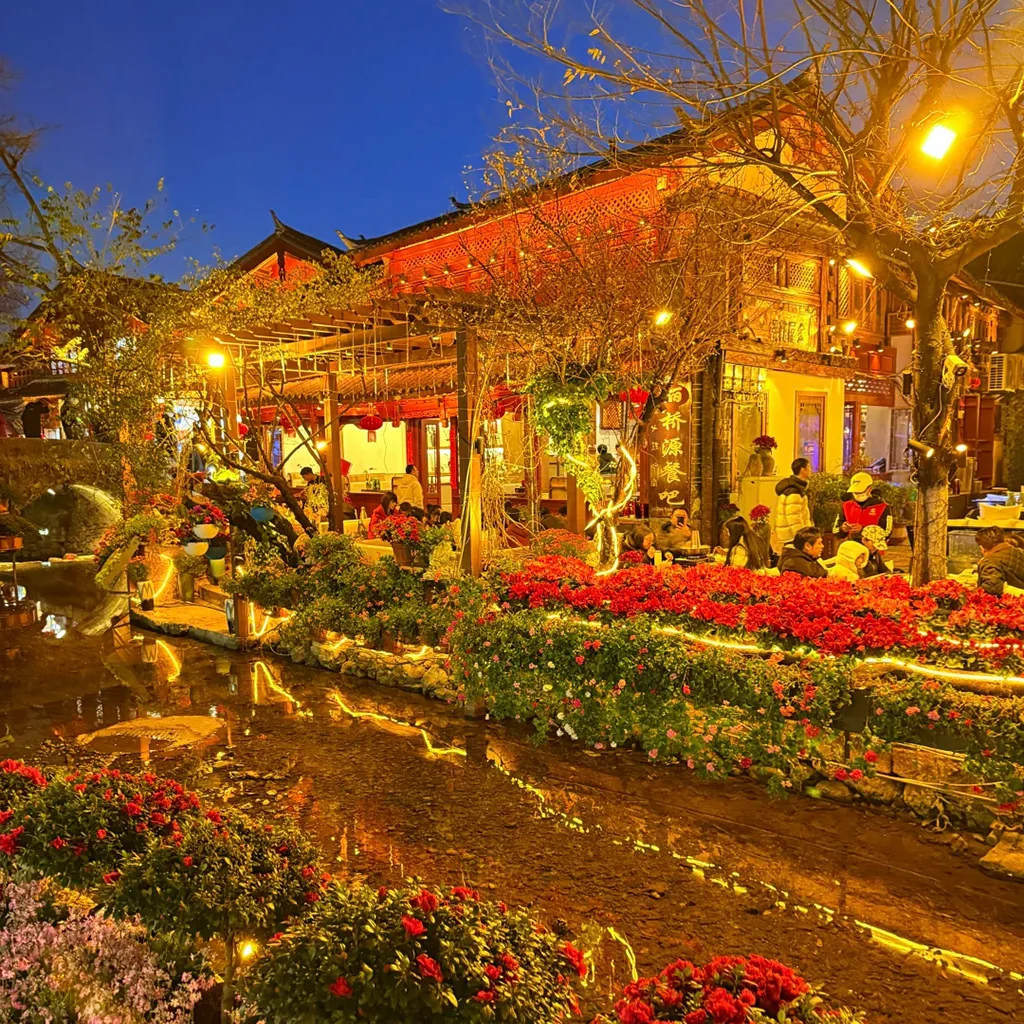 Lijiang Old Town2 夜晚的 麗江古城 燈火通明,小橋流水與花卉點綴其間,街邊餐廳與遊客交織,營造出溫馨浪漫的古城氛圍。
