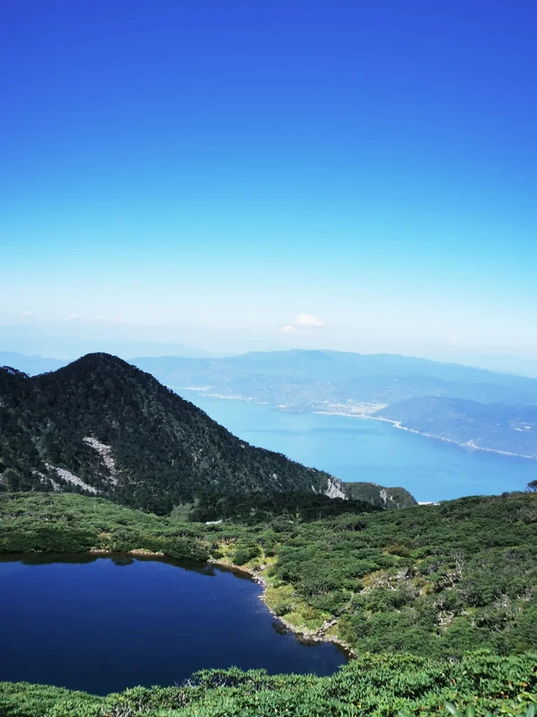 從蒼山俯瞰洱海,山峰與高山湖泊交織,遠方湖水蔚藍壯麗。