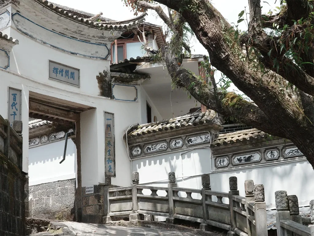 Tengchong Heshun Ancient Town 3 騰衝和順古鎮的白族傳統民居,白牆藍邊、飛檐翹角,古榕樹的枝椏斜倚在屋頂,是滇西僑鄉建築風情的典型模樣。