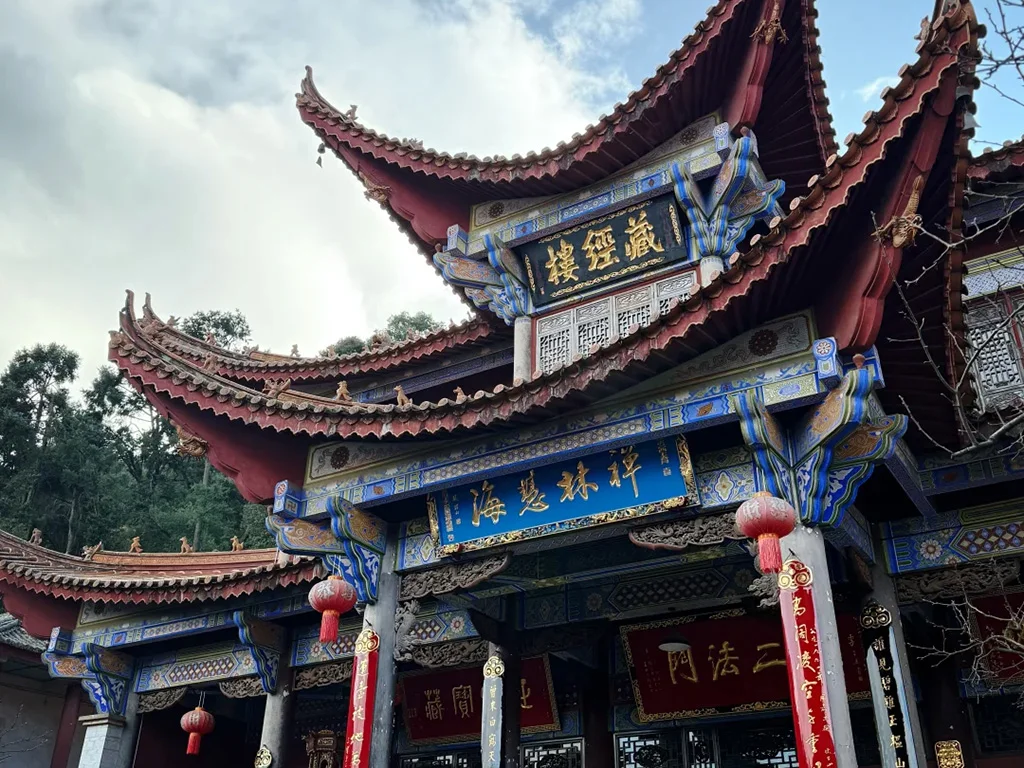昆明西山華亭寺的藏經樓,飛檐翹角的傳統中式建築,彩繪樑柱與紅燈籠相映,是西山深處充滿禪意的古剎景點。
