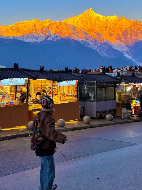 在飛來寺市集的街頭，與梅里雪山「日照金山」奇景同框，金色的雪峰與暖黃的市集燈光相映，是滇西旅行最神聖的瞬間。