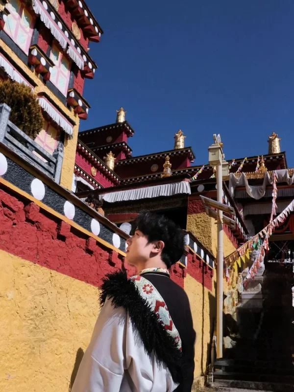在松贊林寺的紅黃牆前，穿著藏服側身而立，寺廟的金頂與經幡相映，是香格里拉最具藏式氛圍的打卡畫面。